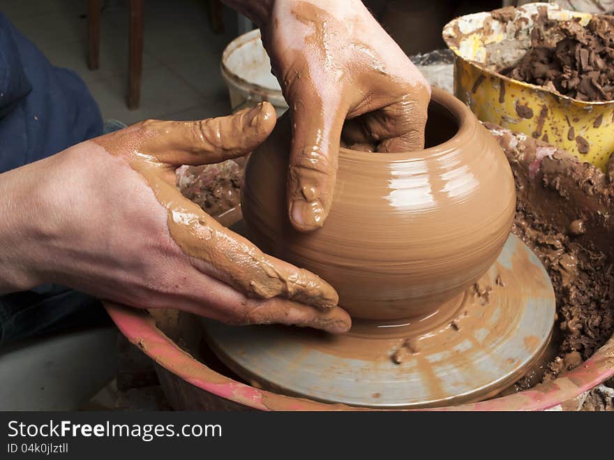 Hands of a potter, creating an earthen jar