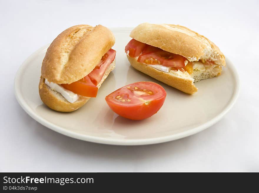 Buns on a plate filled with cheese and tomatoes, two and a half rolls stuffed tomato on a plate on a white background. Buns on a plate filled with cheese and tomatoes, two and a half rolls stuffed tomato on a plate on a white background