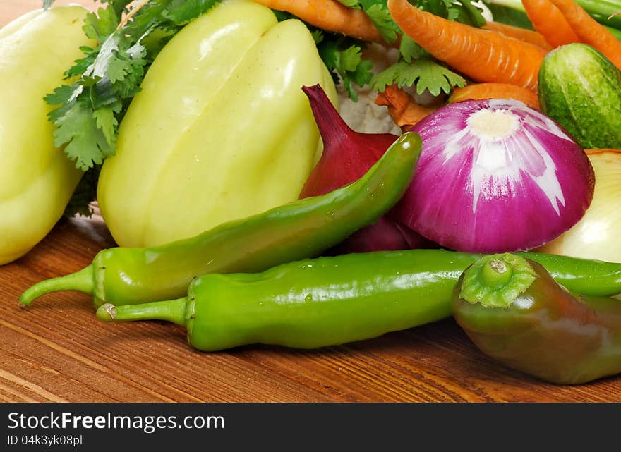 Vegetable Set of Green Bell Pepper, Chili peppers, Red Onion, Carrot and greens closeup on wooden background