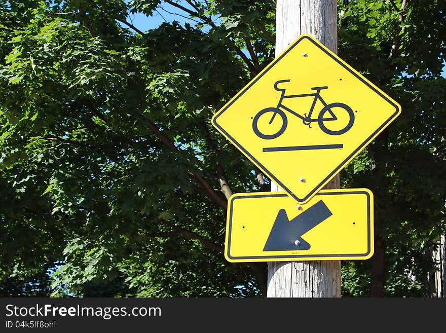 Yellow bicycle path street sign with trees in background. Yellow bicycle path street sign with trees in background