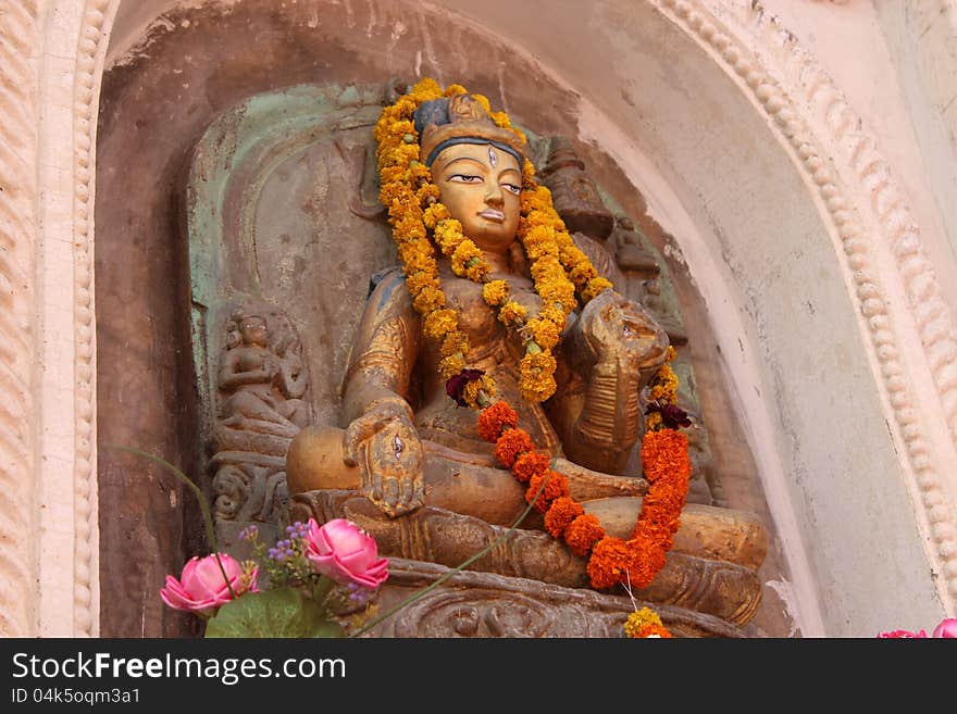 Buddhist statue (Tibetan style) with flower garland in Bodh Gaya where the Buddha became enlightened