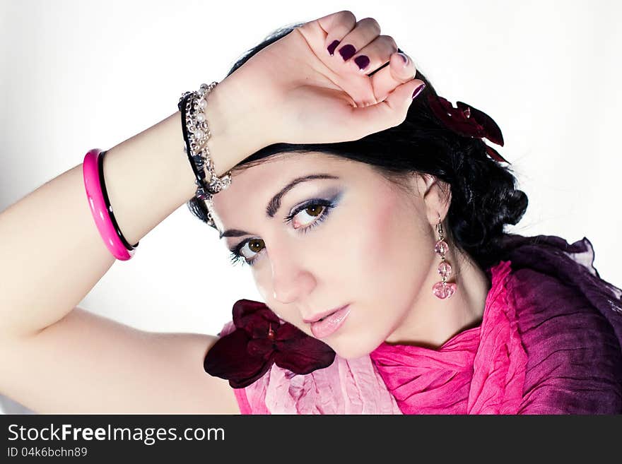 Portrait of beautiful young brunette woman in pink dress, bracelet and orchid. Portrait of beautiful young brunette woman in pink dress, bracelet and orchid