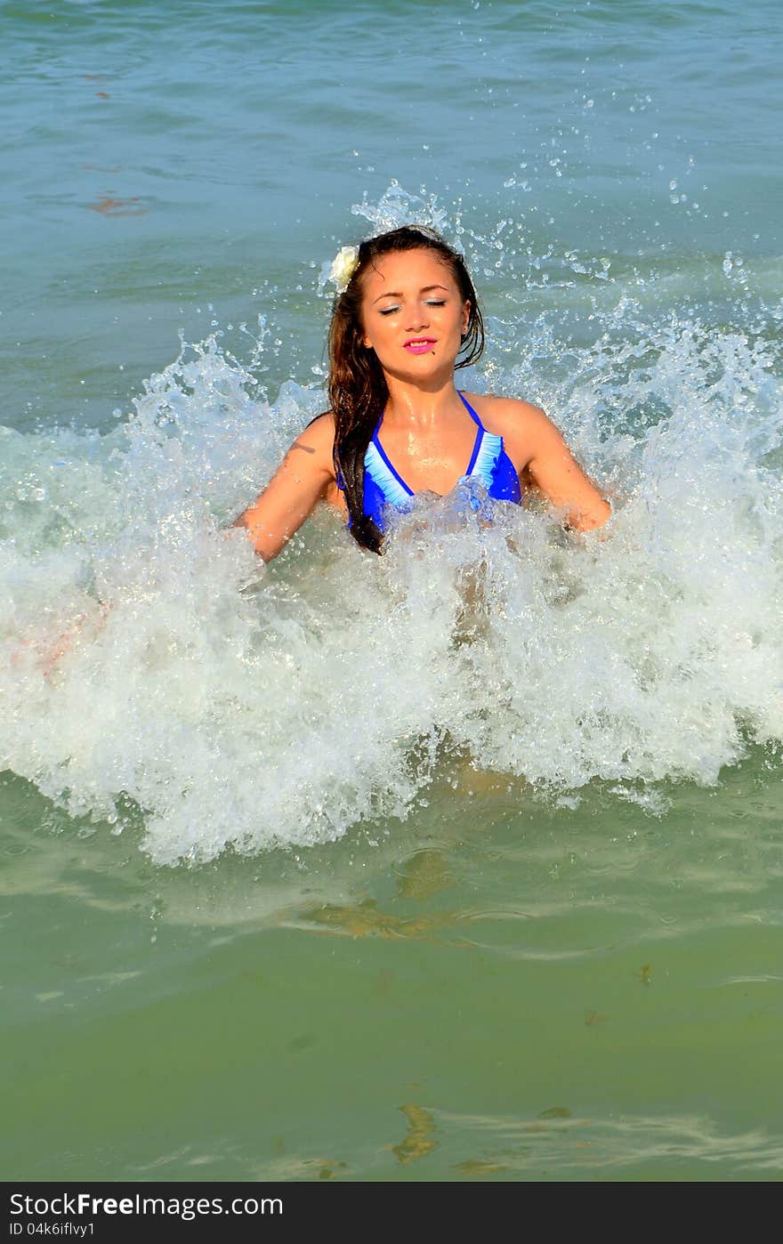 Image of a girl standing in the wave splashing water around her