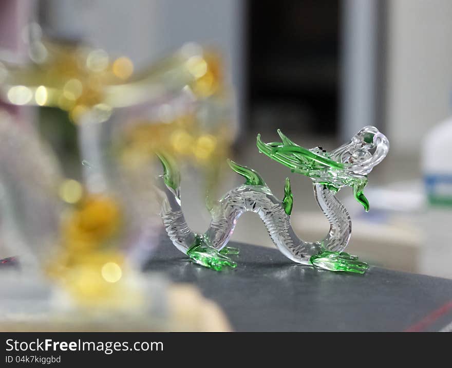 Close up of glass dragon. Focus from soft to sharp emphasizing the dragons head and green skin. Close up of glass dragon. Focus from soft to sharp emphasizing the dragons head and green skin.