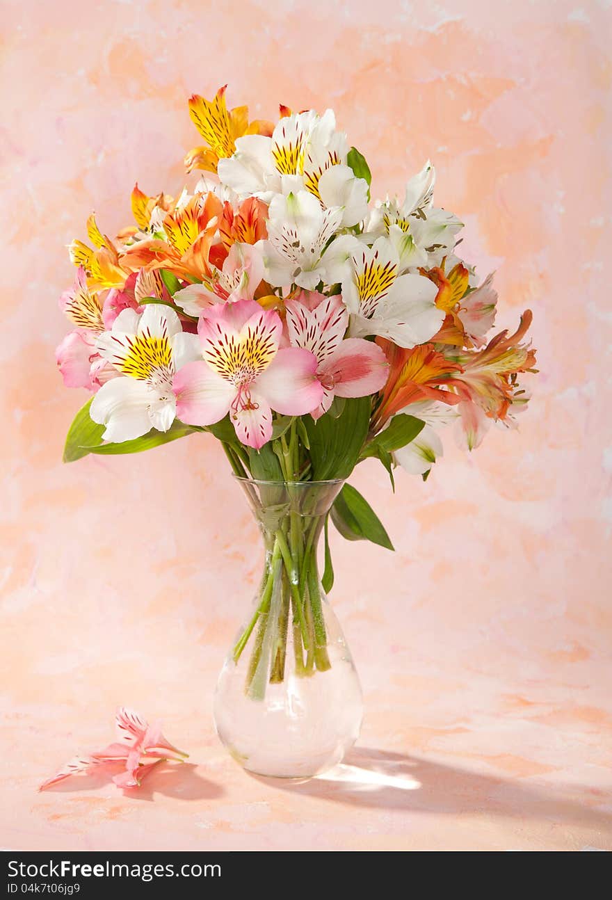 Bouquet of Alstroemeria in a transparent glass vase on abstract background