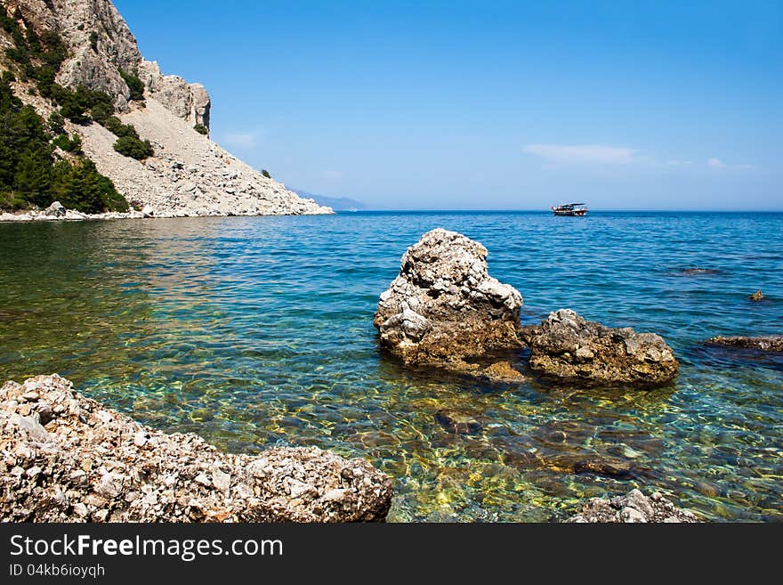 The yacht sails from the rocky sea coast. Marmaris. Turkey.