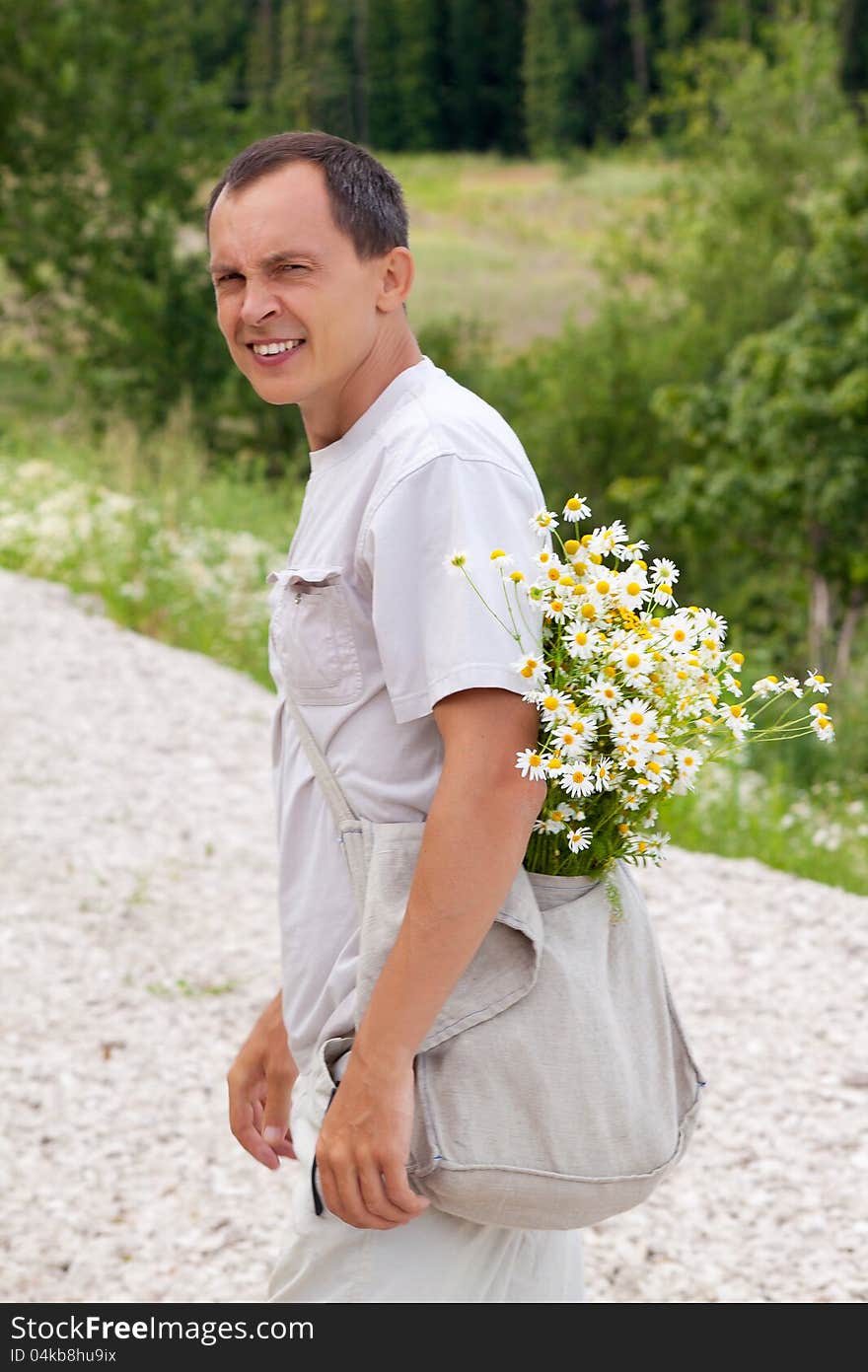 The young man with camomiles in a bag looks back