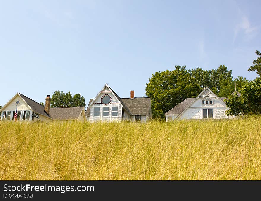 A row of beach houses near beach grass in the summer time.