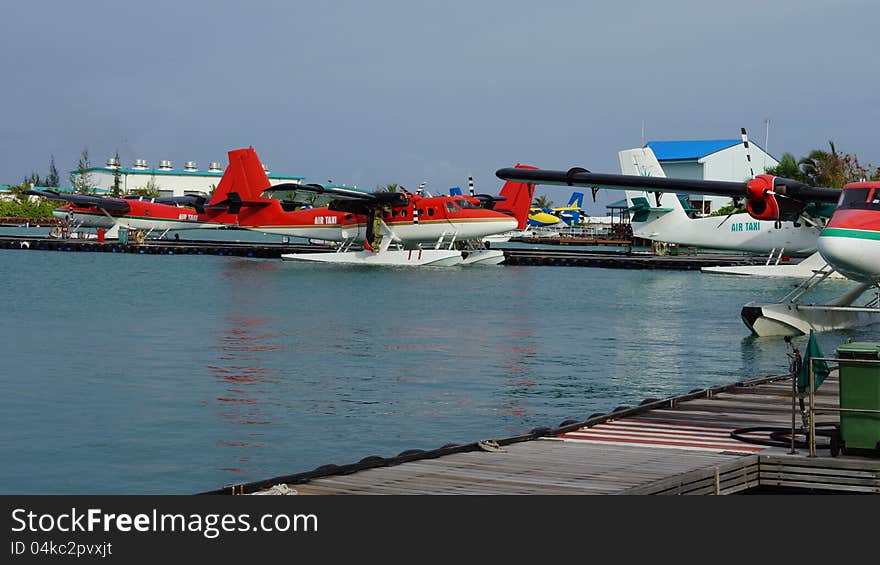 Pontoon planes or floatplanes moored in the sea alongside a jetty eqipped with pontoons to land on water. Pontoon planes or floatplanes moored in the sea alongside a jetty eqipped with pontoons to land on water