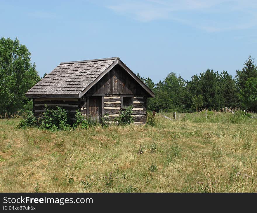 Old log shack in a field.