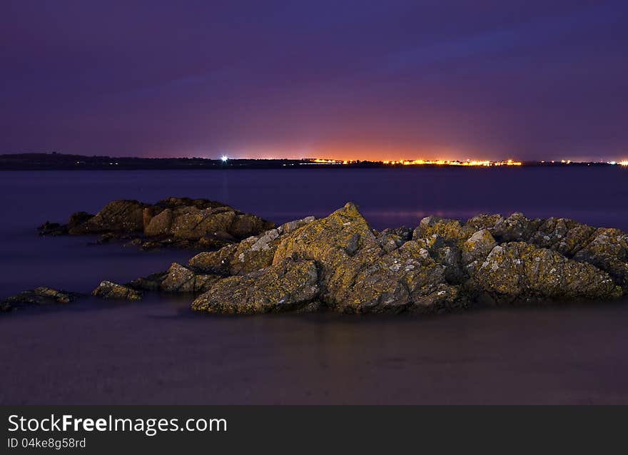 Seaside. Coast at night in Skerries, Ireland. Rocks in water. long exposure.