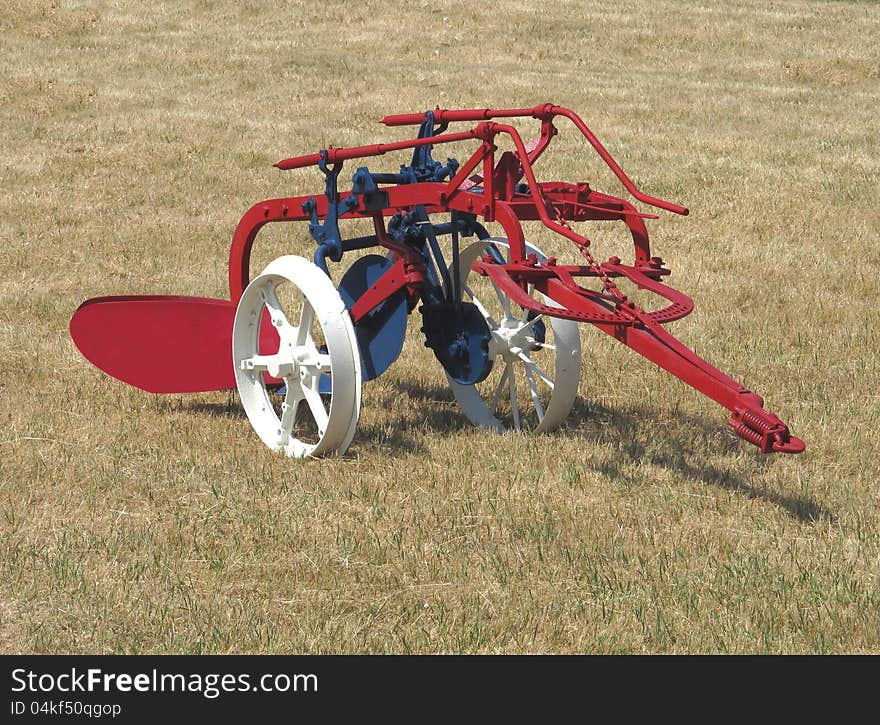 Old farming plow in a field isolated.