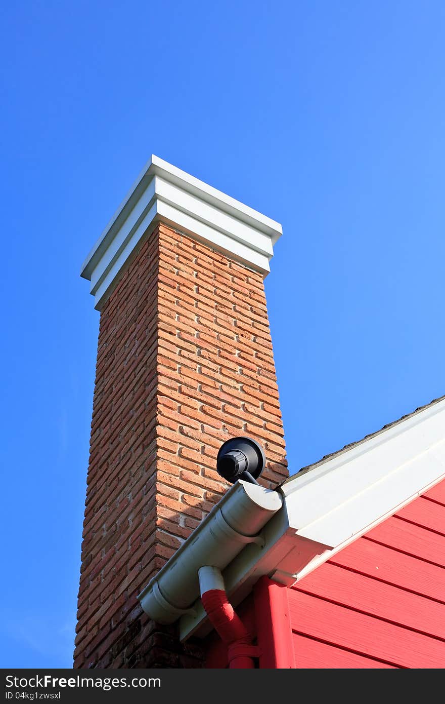 Orange brick pipe and black roof on blue sky