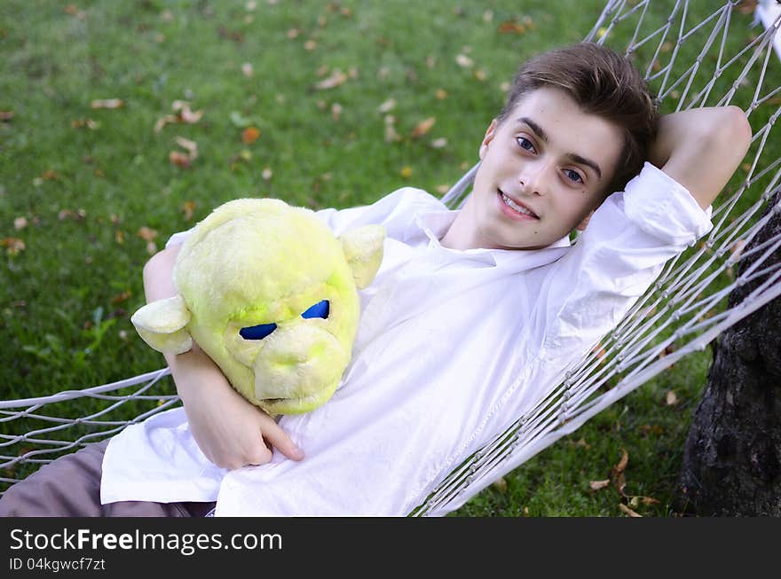 Young man resting in a hammock, holding monkey mask in his hand. Young man resting in a hammock, holding monkey mask in his hand