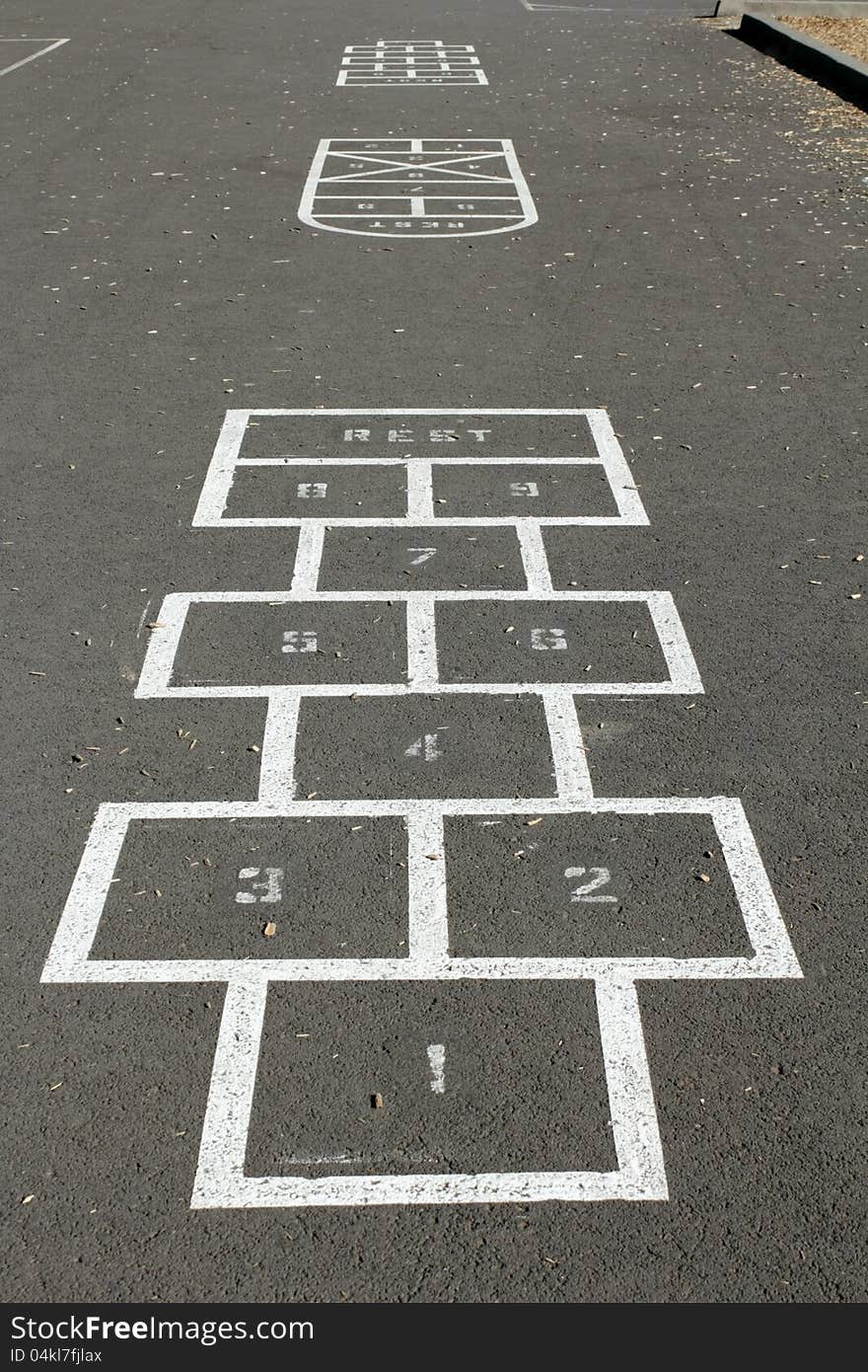 A few hopscotch game courses are outlined on the pavement of a children's playground on a sunny morning. A few hopscotch game courses are outlined on the pavement of a children's playground on a sunny morning.