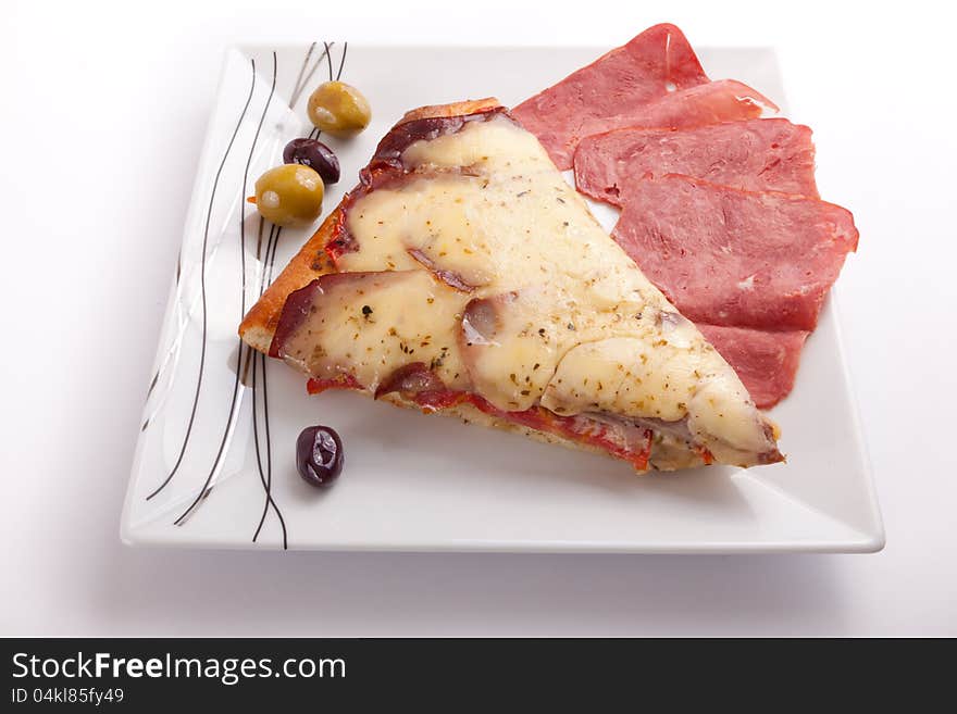 Pizza slice with olive and salami on a plate on white