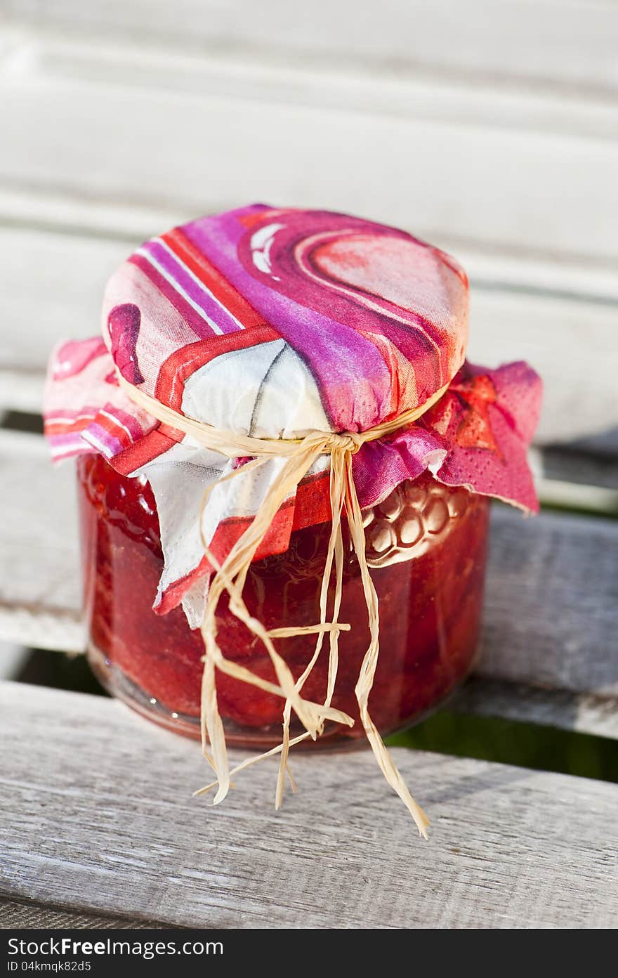 Strawberry jam in a glass on wood