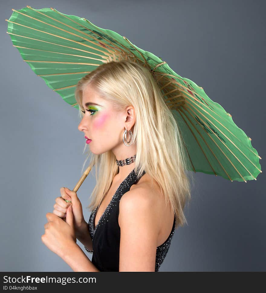 An image of a made-up teen in a fancy dress, holding a parasol. An image of a made-up teen in a fancy dress, holding a parasol