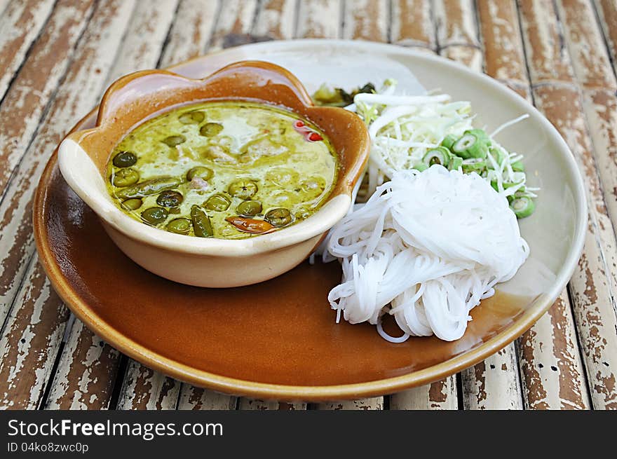 Rice noodle with ckicken green curry (Thai food) on bamboo table