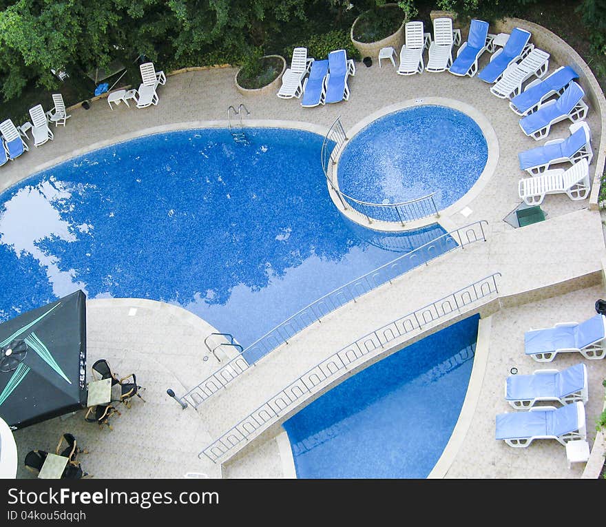 Swimming pool in the hotel with relax chairs and vegetation