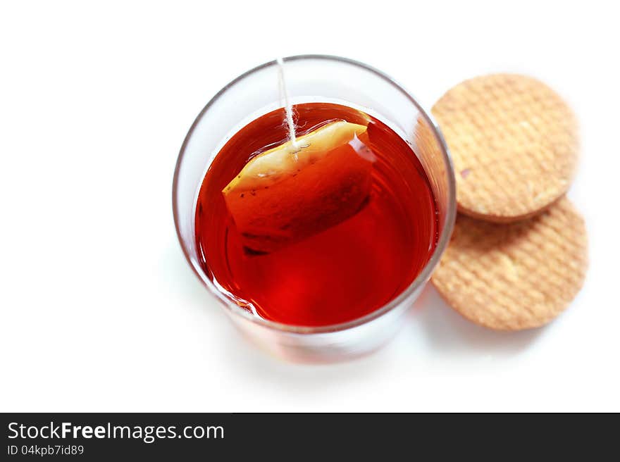 Closeup photo from the top of fresh tea in a glass made of tea powder from tea-bag dipped in water along with cookies. Closeup photo from the top of fresh tea in a glass made of tea powder from tea-bag dipped in water along with cookies