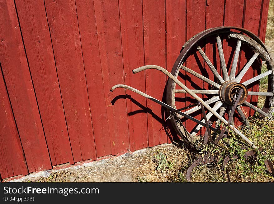 Old Wagon wheel and plow against a red wall. Old Wagon wheel and plow against a red wall