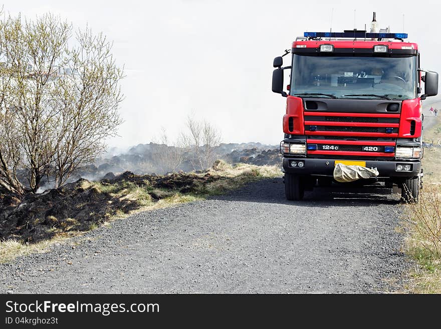 Black and gray grass residues after wildfire. Focus is on the firetruck. Black and gray grass residues after wildfire. Focus is on the firetruck.