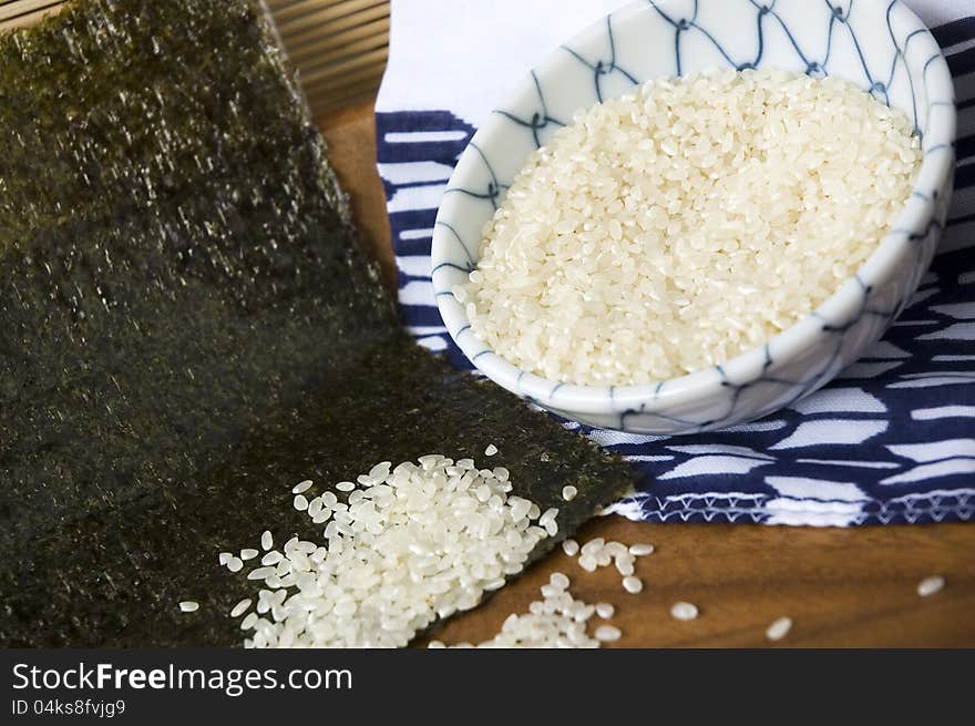 Uncooked japanese rice out of bowl on seaweed