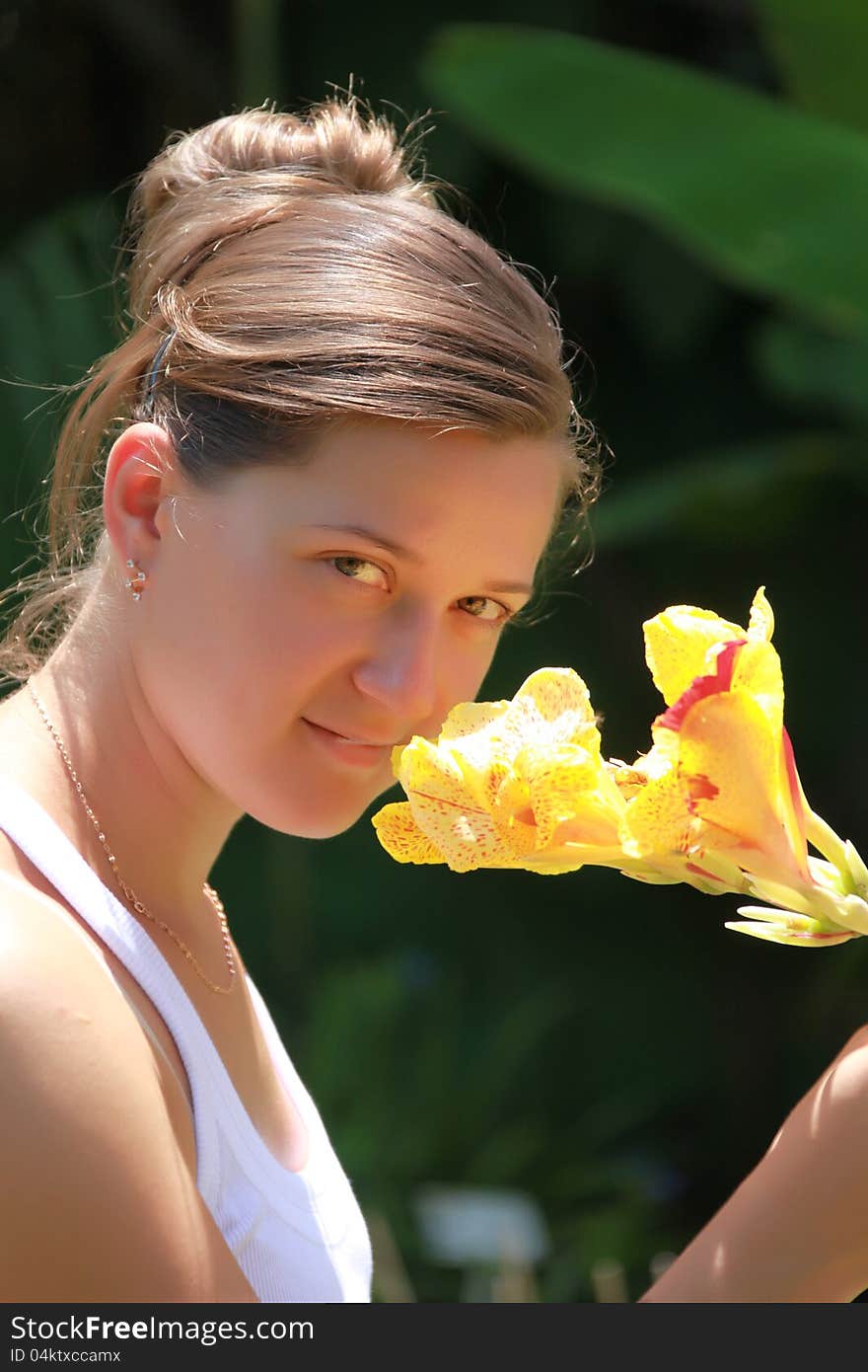 Portrait of a girl with a flower on the outside of the background flora. Portrait of a girl with a flower on the outside of the background flora