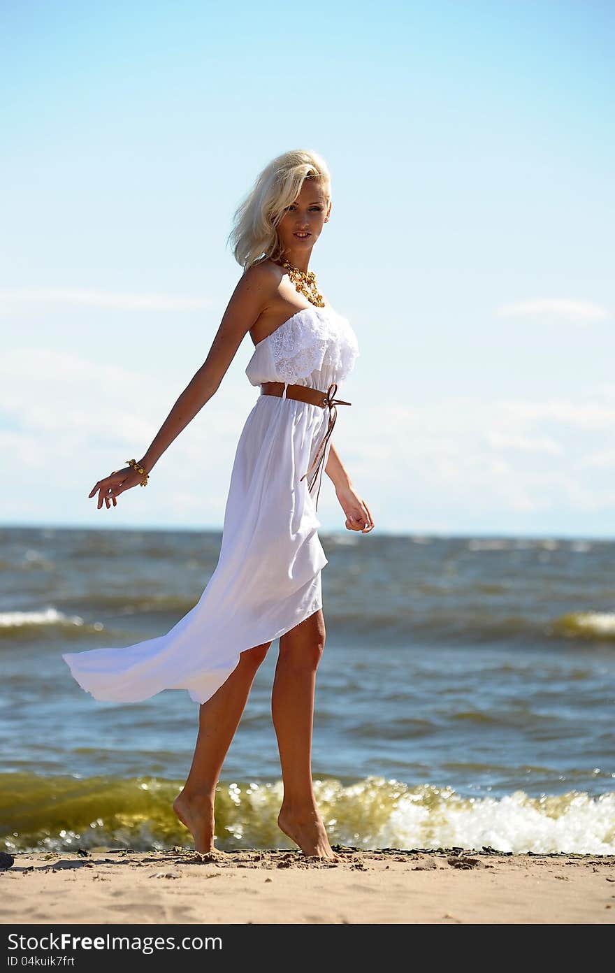 Blonde in a white dress on the beach