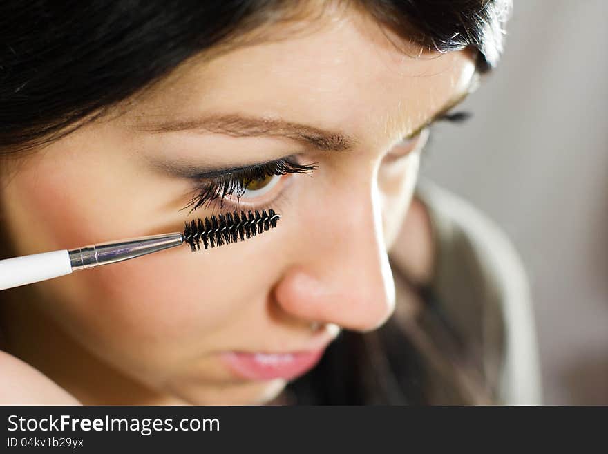 Beautiful woman applying mascara on her eye