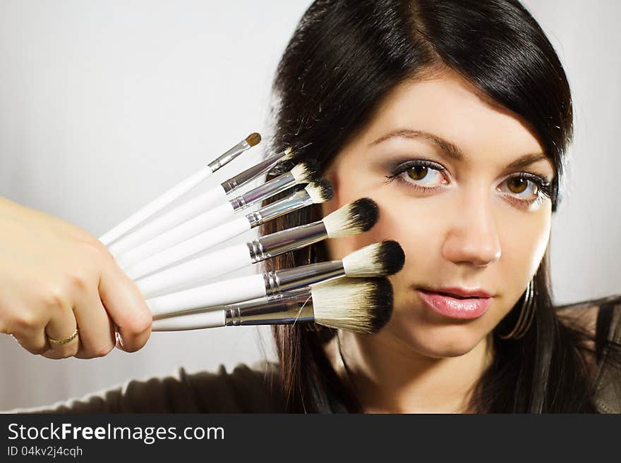 Beautiful woman with makeup brushes