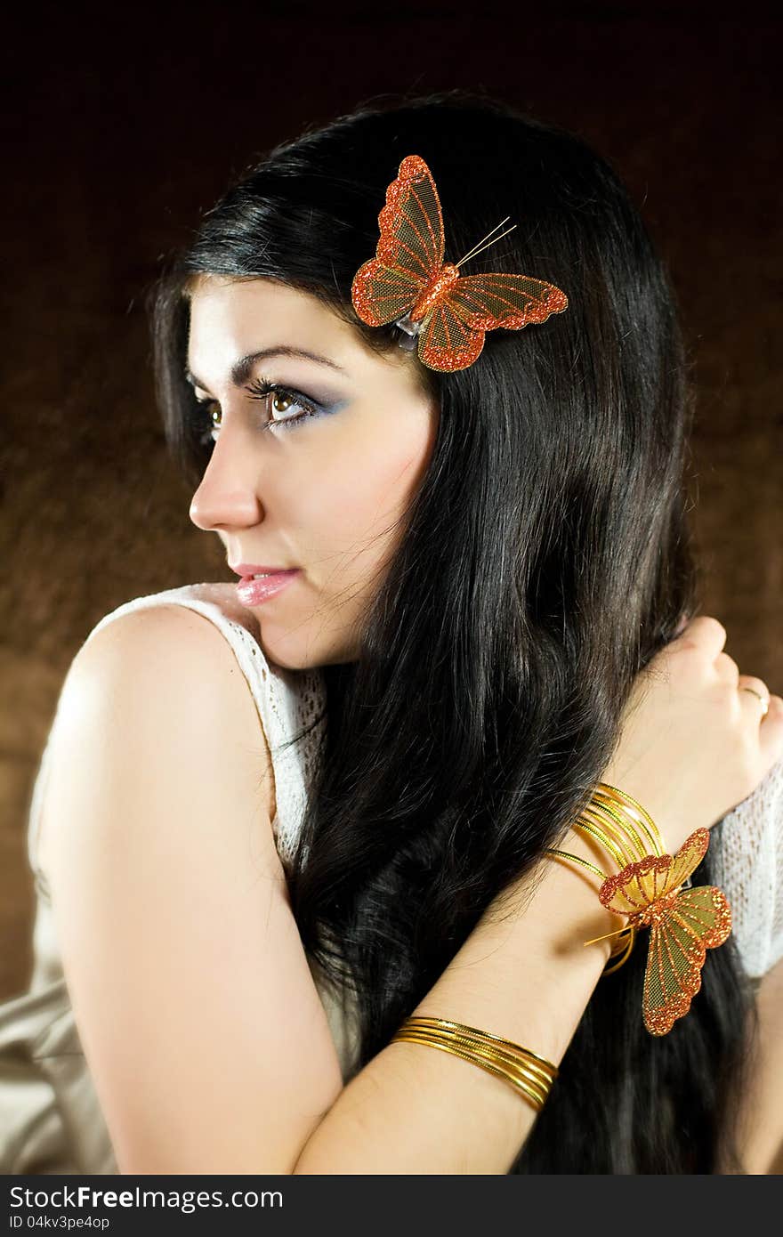 Brunette with brown-gold butterfly against the brown background