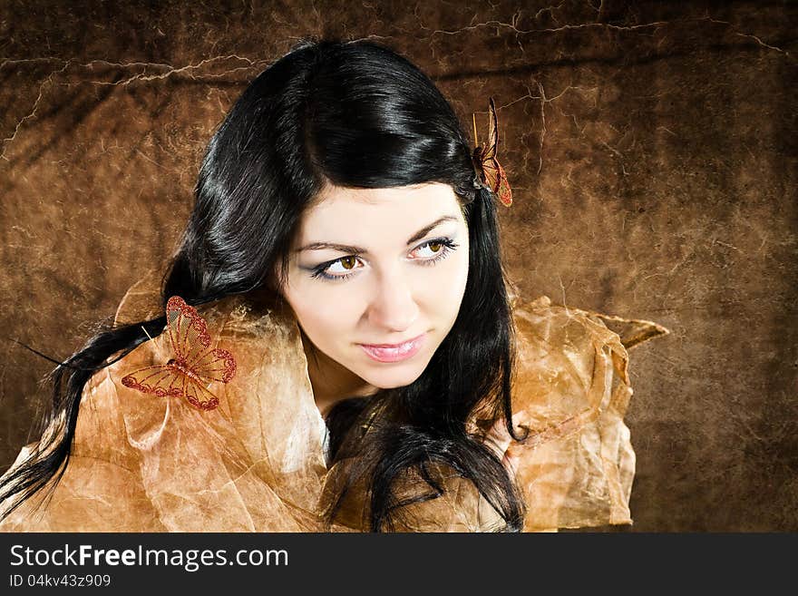 Brunette with brown-gold butterfly against the brown background