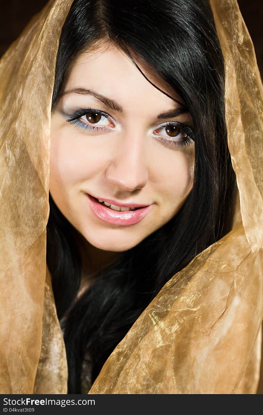 Portrait of young beautiful woman folding brown fabric round her head