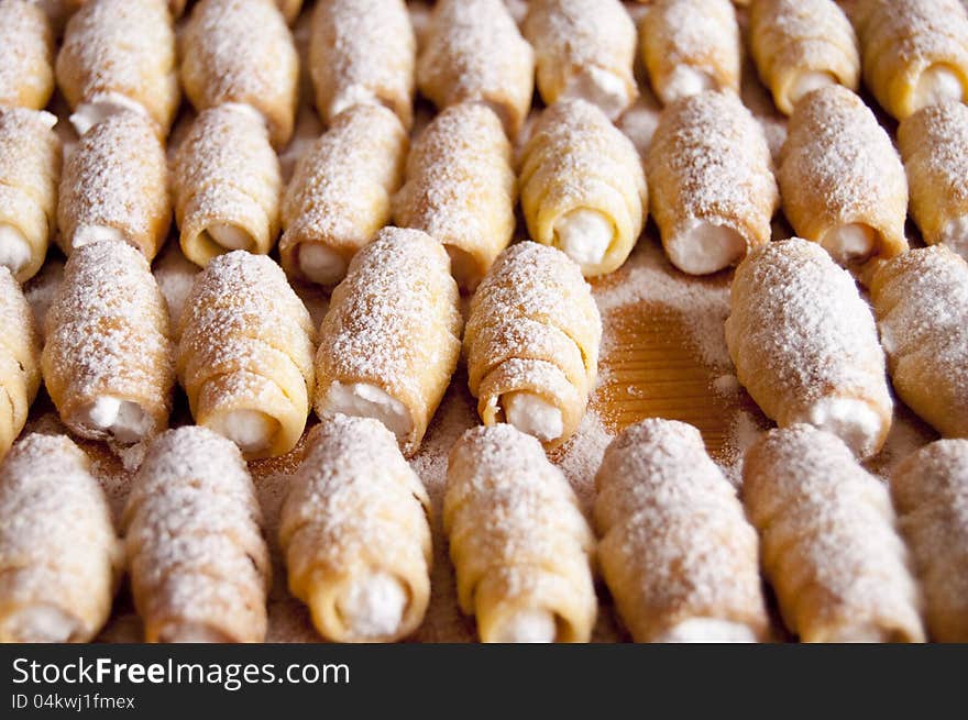 Sweet Cream Rolls on a wooden plate lining in rows.