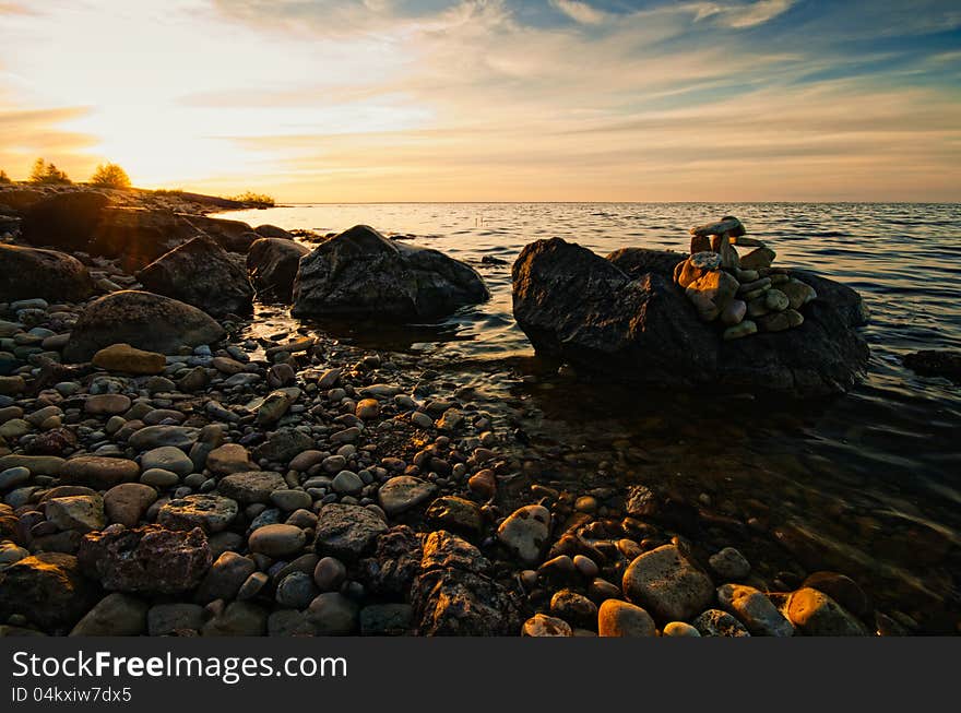 Beautiful sunset on the lake with a rocky shore and the boat. Beautiful sunset on the lake with a rocky shore and the boat