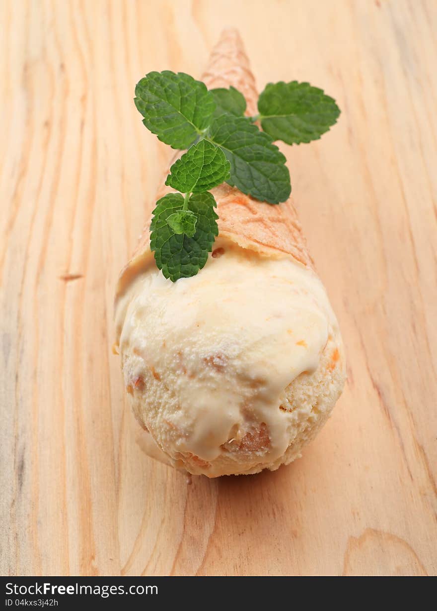 Cone of apricot icecream on wooden background. Cone of apricot icecream on wooden background