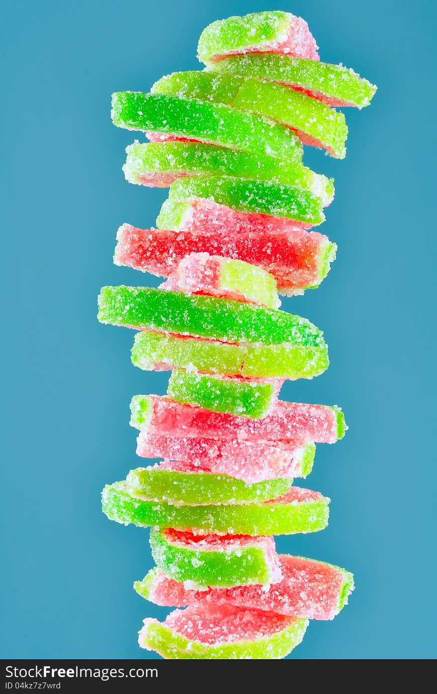 A stack of fruit jelly watermelon candies on a blue background - vertical orientation