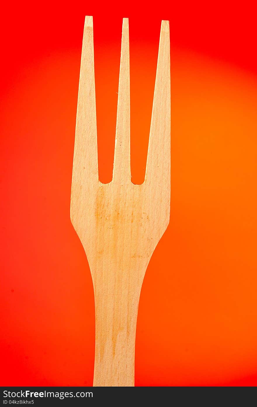 A three-pronged wooden fork on an orange background