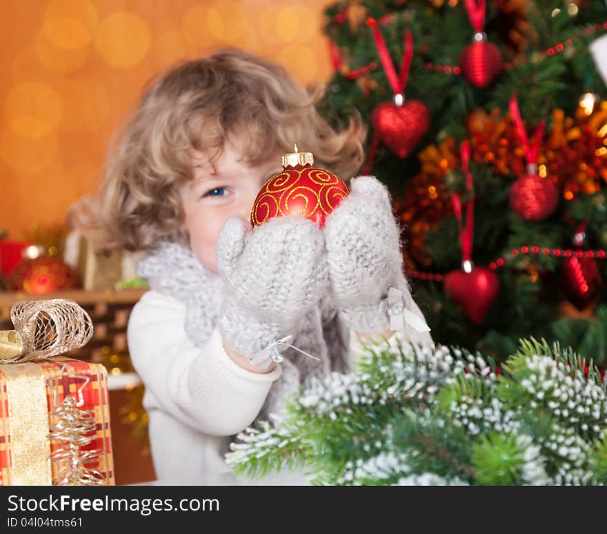 Happy child holding Christmas ball against decorated fir-tree. Happy child holding Christmas ball against decorated fir-tree