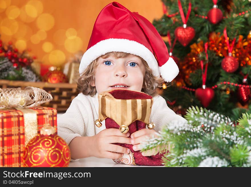 Happy child holding red sock against Christmas tree with decorations. Happy child holding red sock against Christmas tree with decorations