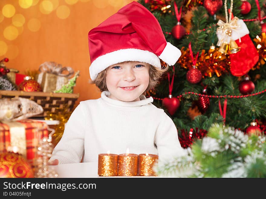 Happy child in Santa`s hat against Christmas tree with decorations. Happy child in Santa`s hat against Christmas tree with decorations