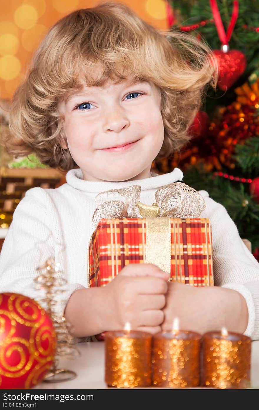 Happy child holding gift box against Christmas tree with decorations