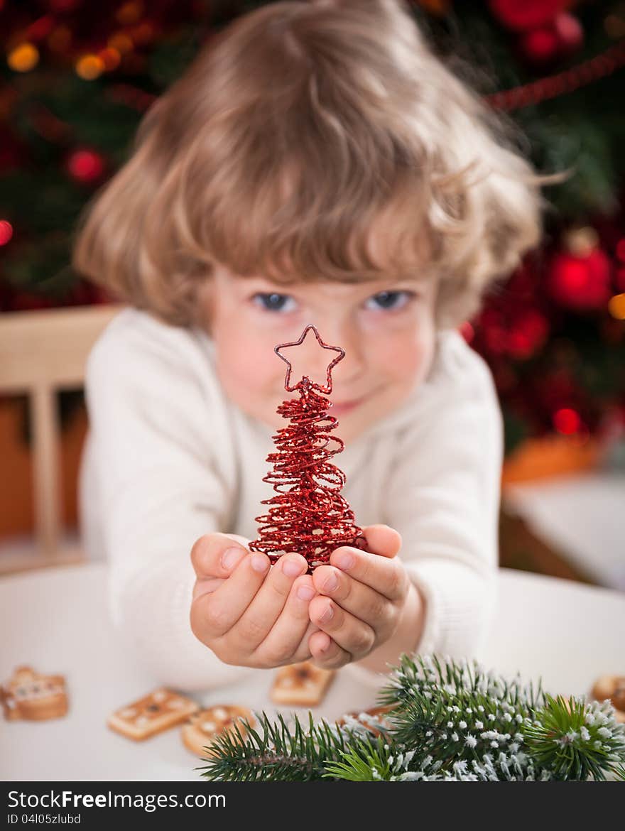 Happy child holding handmade decoration against Christmas lights. Happy child holding handmade decoration against Christmas lights