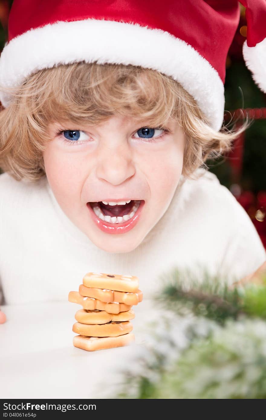 Funny smiling child in Santa`s hat eating Christmas cookies. Funny smiling child in Santa`s hat eating Christmas cookies