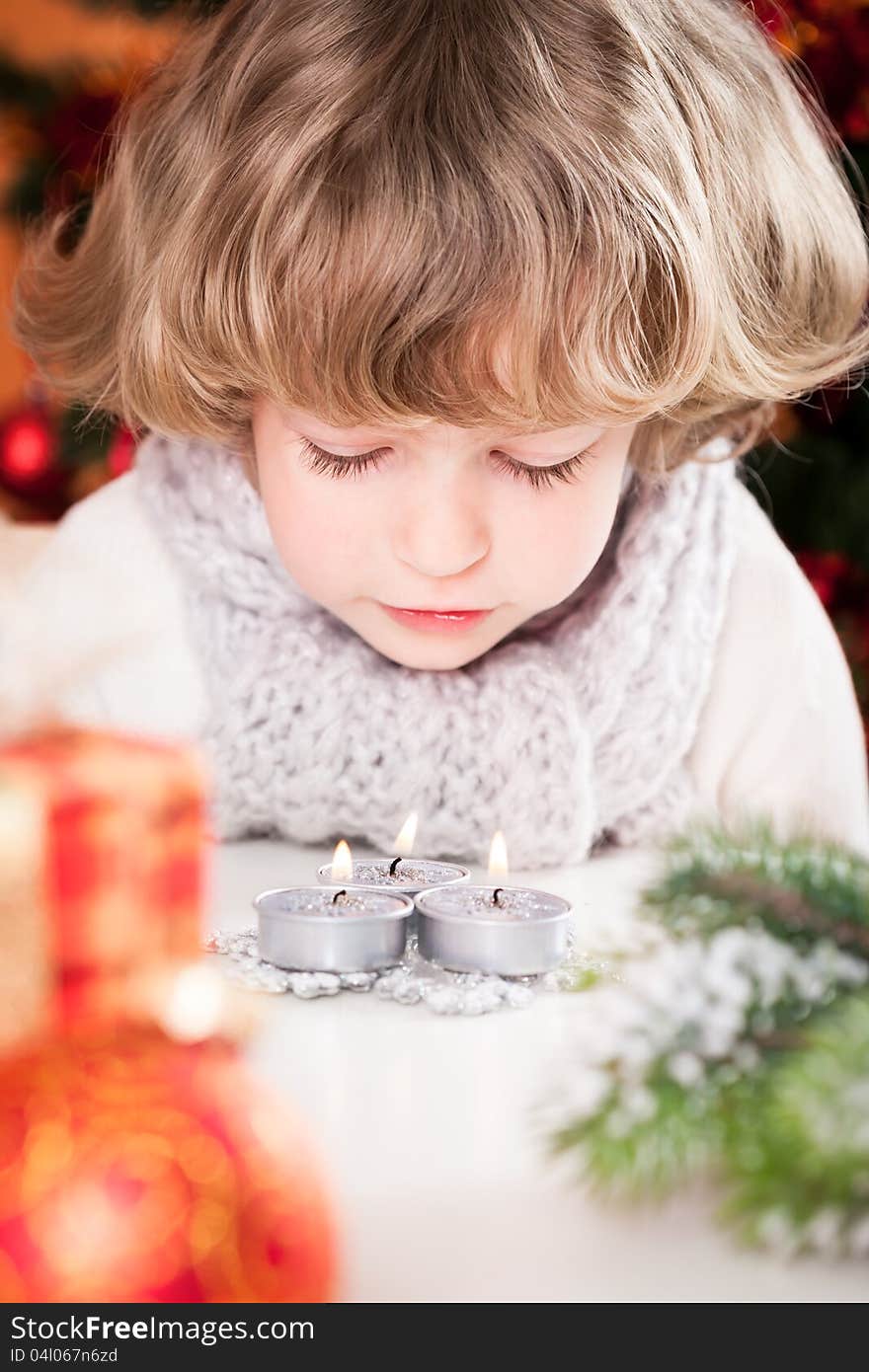 Beautiful child blowing out Christmas candles. Beautiful child blowing out Christmas candles