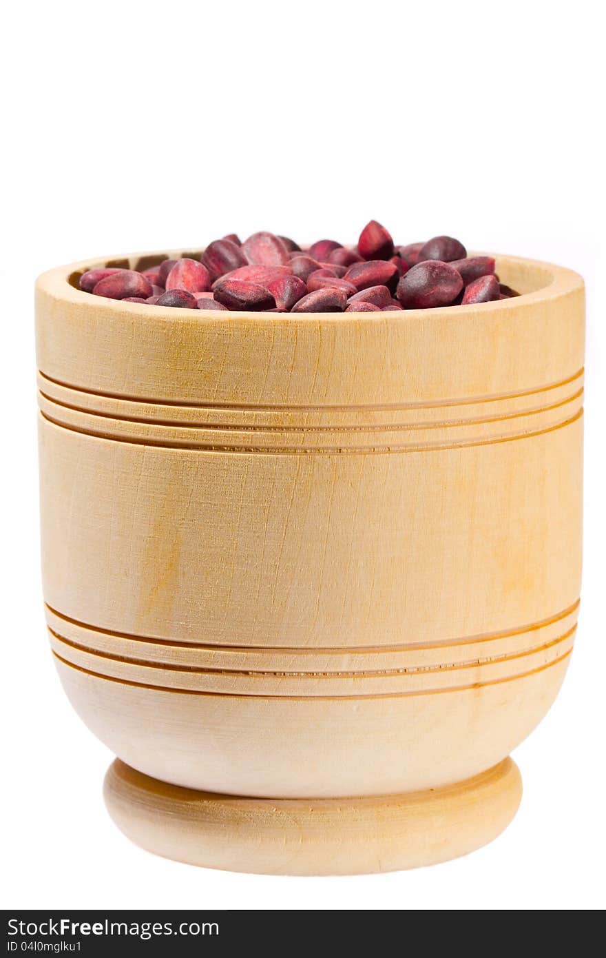 Wooden cup with cedar nuts on white background