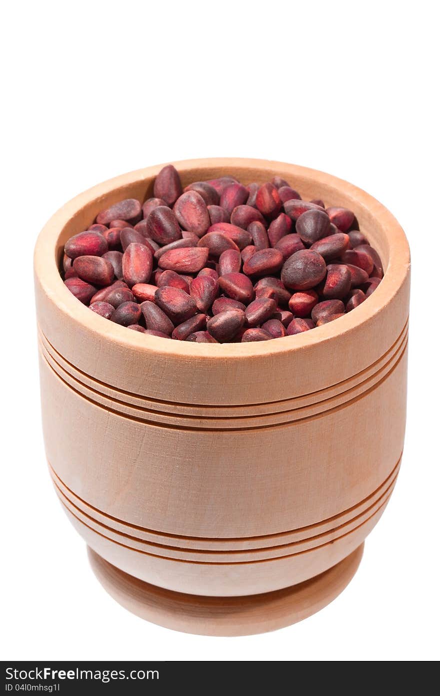 Wooden cup with cedar nuts on white background