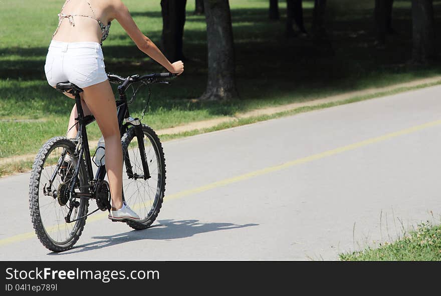 A young woman riding a bicycle on the bike trail in the park. A young woman riding a bicycle on the bike trail in the park